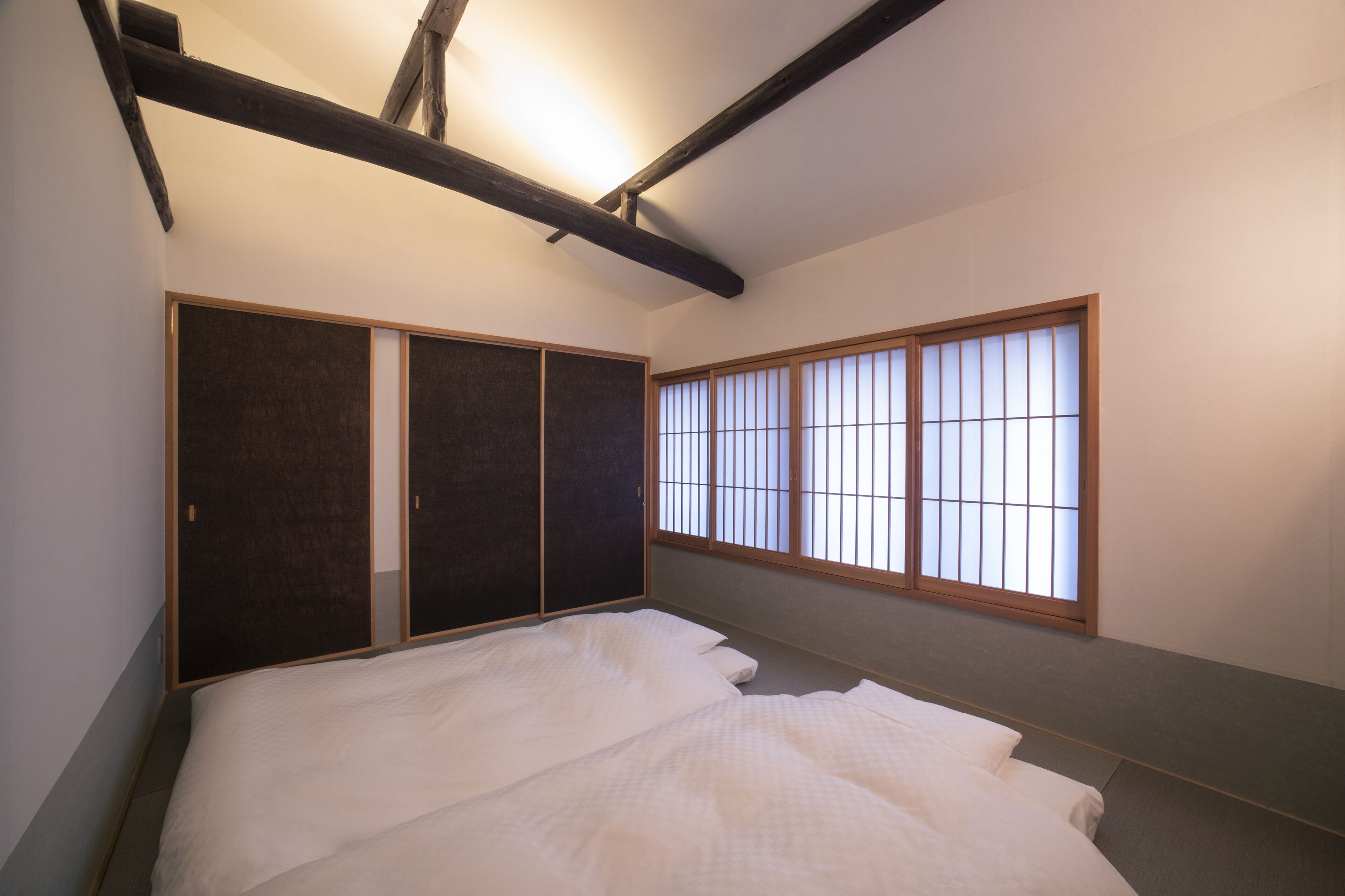 A room with a bed, sliding doors, and a window with vertical blinds.