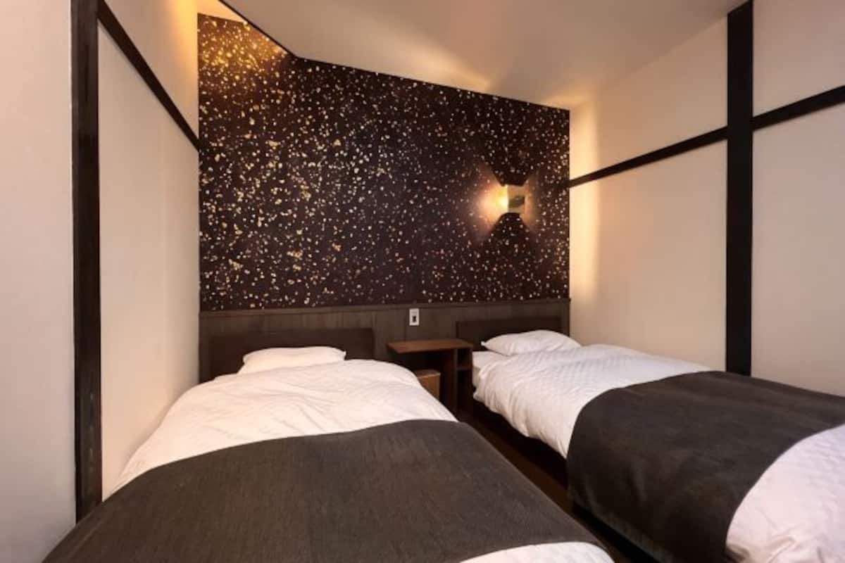 A room with two beds, a starry wall, and a small table.