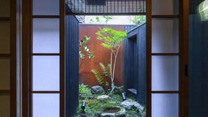 A traditional Japanese garden with a wooden fence, a small tree, rocks, and a water feature. - Rinn Machiya Kuon (Kyoto)