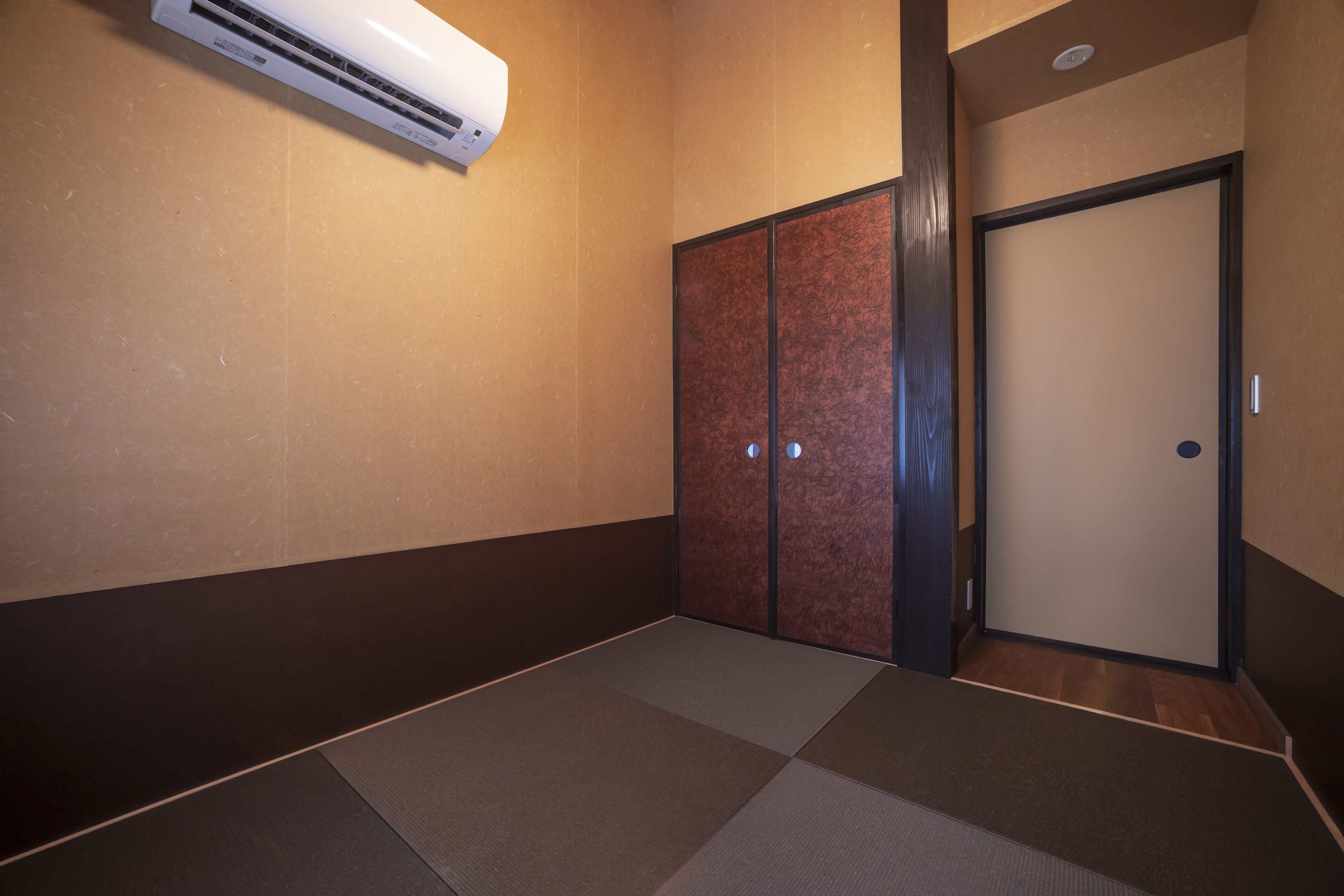 A room with tatami flooring, a sliding door, and an air conditioning unit.