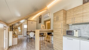 Une cuisine moderne avec des meubles en bois, un four à micro-ondes encastré et un coin repas comprenant une table et des chaises.