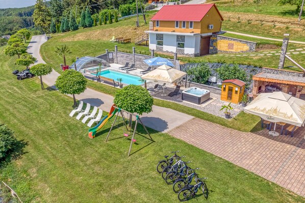 An aerial view of a residential area with a swimming pool, a playground, and a small building with a red roof.