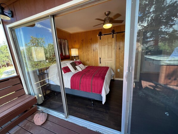A bedroom with a bed, a ceiling fan, and a nightstand with a lamp.