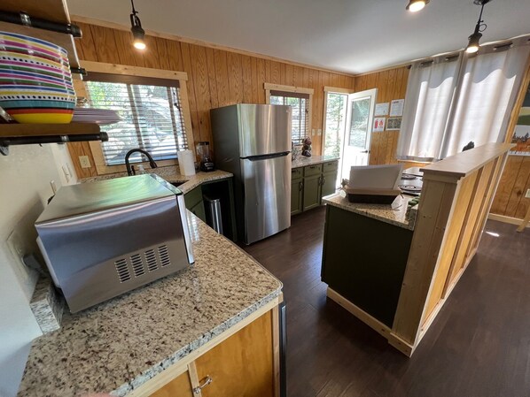 A modern kitchen with granite countertops, stainless steel appliances, and wooden cabinetry.