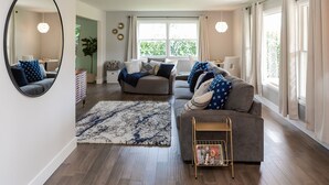 A spacious living room with a large mirror, two sofas, a coffee table, and a magazine rack. - Eye-catching Home and Yard w/ Luxurious Hot Tub, Patio, and Private Trail Access (Port Angeles)