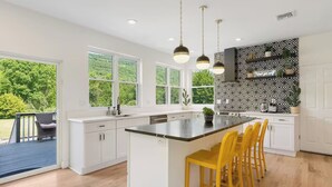 A modern kitchen with a large island, white cabinetry, and a black and white patterned backsplash.