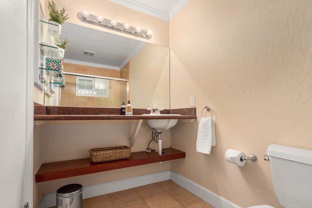 A bathroom with a vanity, sink, mirror, towel rack, and toilet.