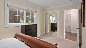 A bedroom with a bed, dresser, and a sliding glass door leading to a bathroom.