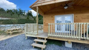 Situated on a gravel surface, this cabin features a simple design with a sloped roof and a single window.