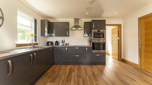 Una cocina moderna con armarios oscuros, electrodomésticos de acero inoxidable y piso de madera.