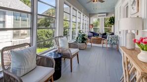 A sunroom with wicker furniture, large windows, and a ceiling fan. - Cozy Family Home Close to the Beach (Tybee Island)