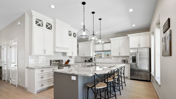 A modern kitchen with white cabinets, a large island with bar stools, stainless steel appliances, and pendant lighting. - Luxury Coastal Escape • Heated Pool & Hot Tub • 2 Min Walk to Beach (South Padre Island)