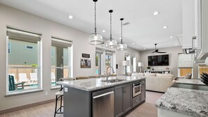 A modern kitchen with a central island, stainless steel appliances, and pendant lighting. - Luxury Coastal Escape • Heated Pool & Hot Tub • 2 Min Walk to Beach (South Padre Island)