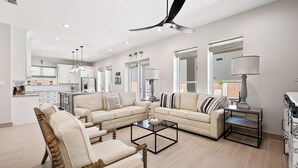 A spacious living room with two sofas, a coffee table, and a dining area with a chandelier. - Luxury Coastal Escape • Heated Pool & Hot Tub • 2 Min Walk to Beach (South Padre Island)