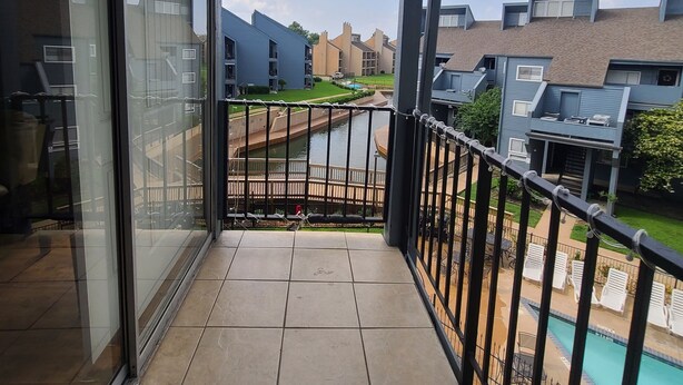 A balcony with a view of a swimming pool and adjacent buildings. - Relaxing Lake Conroe Condo overlooking the pool and lake (Montgomery)
