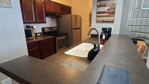 A kitchen with dark granite countertops, stainless steel appliances, and wooden cabinets. - Relaxing Lake Conroe Condo overlooking the pool and lake (Montgomery)