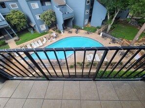 A residential building with a swimming pool surrounded by lounge chairs and a small garden area. - Relaxing Lake Conroe Condo overlooking the pool and lake (Montgomery)
