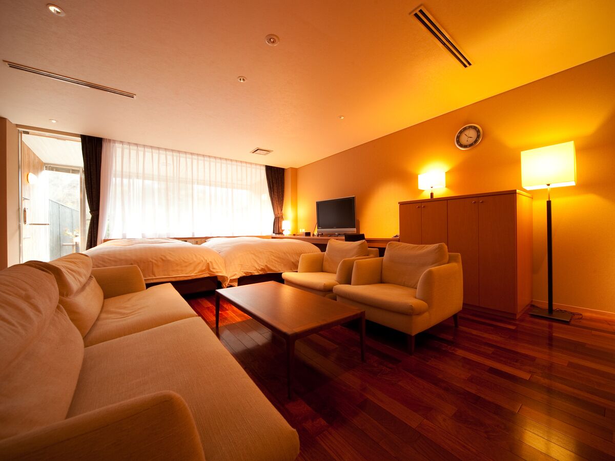A hotel room with a large bed, two sofas, a coffee table, a TV, and a wardrobe.