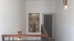 A staircase with a wooden handrail and a metal balustrade, leading to a room with a large abstract painting on the wall and a lit wall sconce. - Quinta Alberto Boutique Hotel (San Blas)