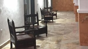 A hallway with a series of wooden chairs aligned against the walls, a ceiling fan, and a tiled floor. - Quinta Alberto Boutique Hotel (San Blas)