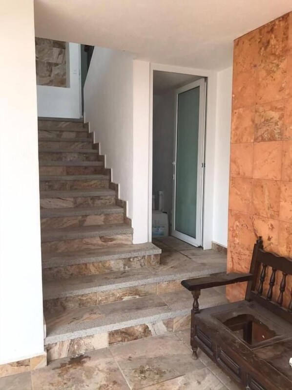 A staircase leading to a second floor, a wooden bench, and a door to another room.