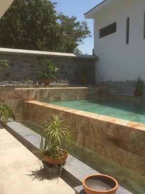 A swimming pool with a stone wall and potted plants. - Quinta Alberto Boutique Hotel (San Blas)