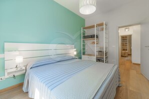 Une chambre à coucher comprenant un lit, des tables de chevet, une armoire et un dressing.