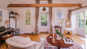 A spacious living room with a piano, a round coffee table, and a comfortable sofa. - Little Pontus (Canterbury)