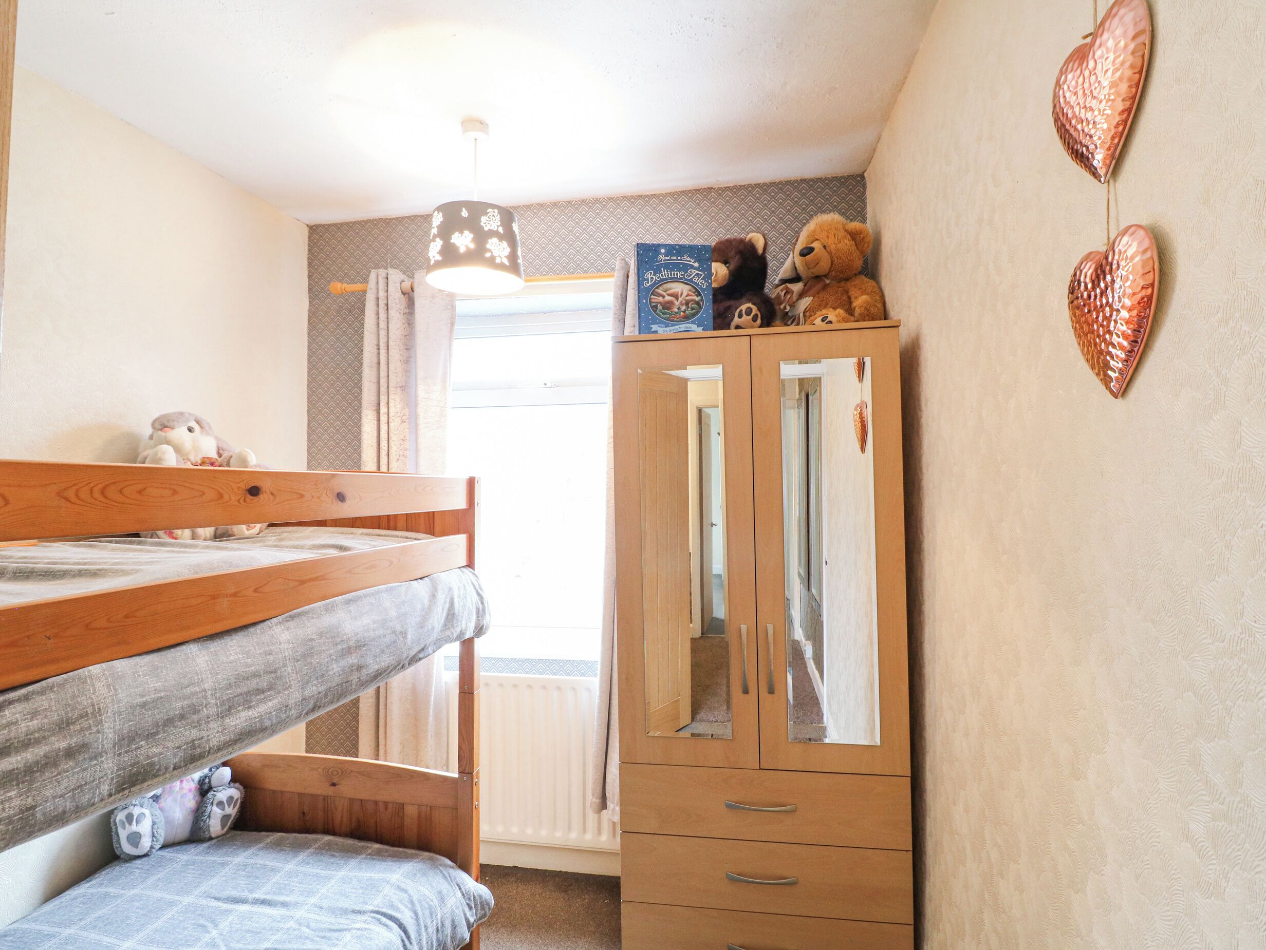 A bedroom with a bunk bed, a wardrobe, and a mirror.
