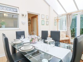 A dining area with a glass table set for six, surrounded by black chairs.