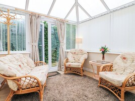 A conservatory with wicker furniture, a small table, and a vase of flowers.