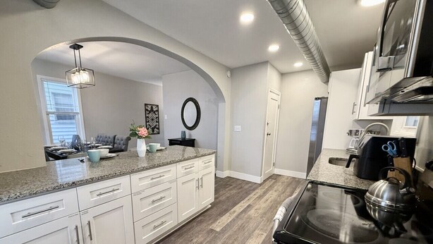 A modern kitchen with white cabinets, a granite countertop, and a stainless steel stove.