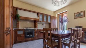 Une cuisine avec des meubles de rangement en bois, une cuisinière et une table à manger avec des chaises.