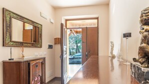 Un couloir doté d’un plancher en bois, d’un grand miroir, d’une armoire et d’une statue.