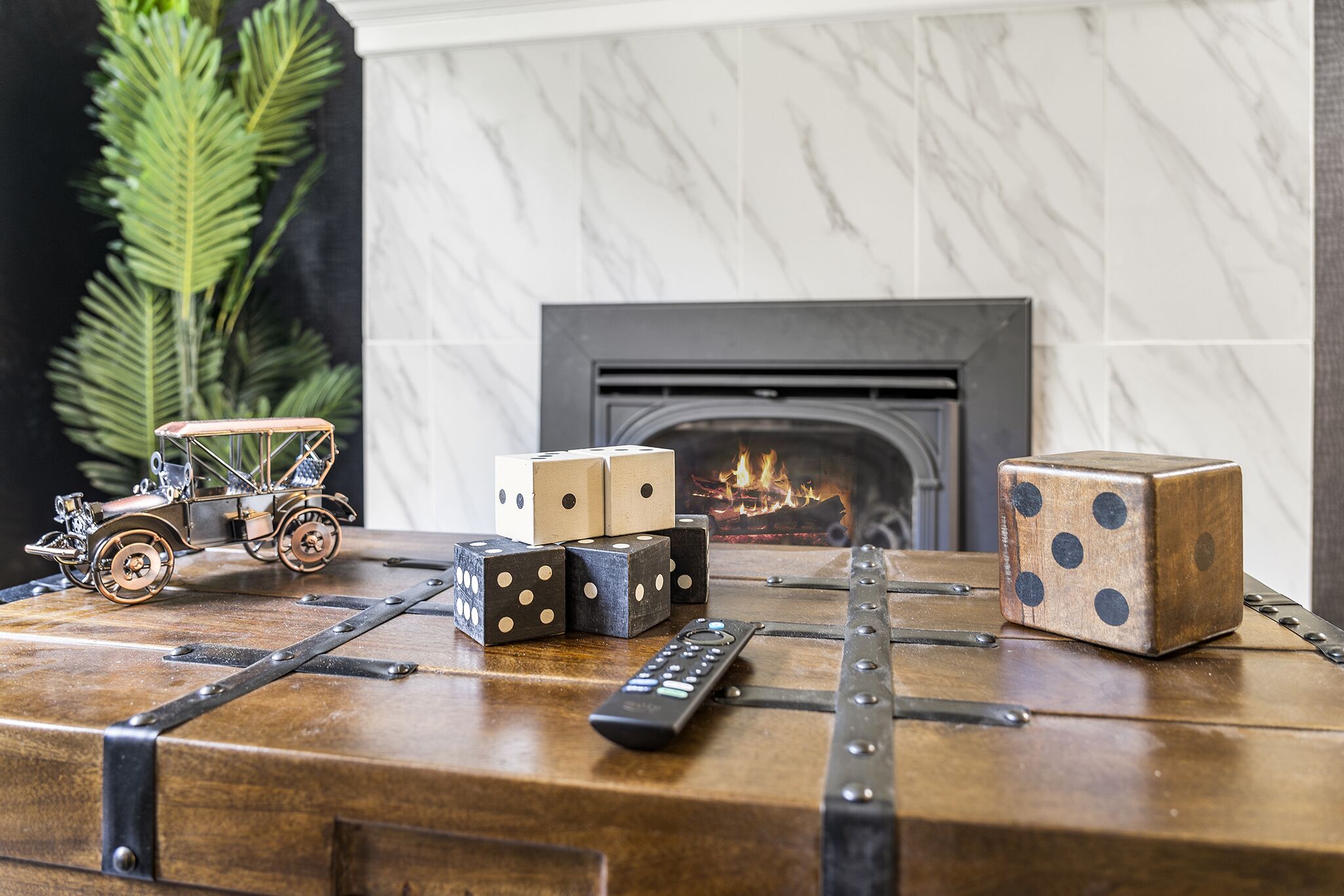 A wooden table with a vintage toy car, dice, and a remote control.