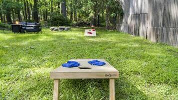 A GoSports mini disc golf basket in a grassy backyard with a wooden fence and a couch in the background.