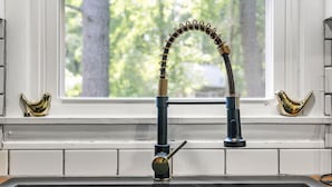 A kitchen sink with a modern faucet and a window above it. - Retro Countryside Cabin | Cozy Upstate NY Private Retreat! (Eldred)