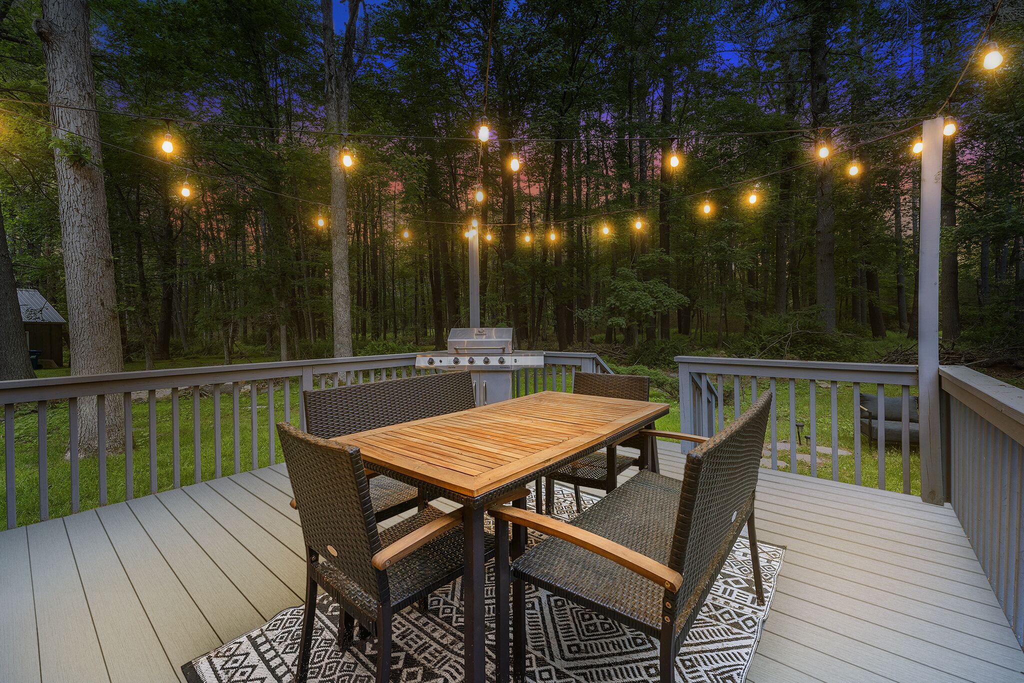 A wooden deck with a table and chairs, surrounded by a forest.
