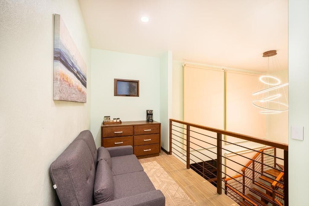 Una sala de estar moderna con un sofá, un aparador de madera y una escalera con barandilla.
