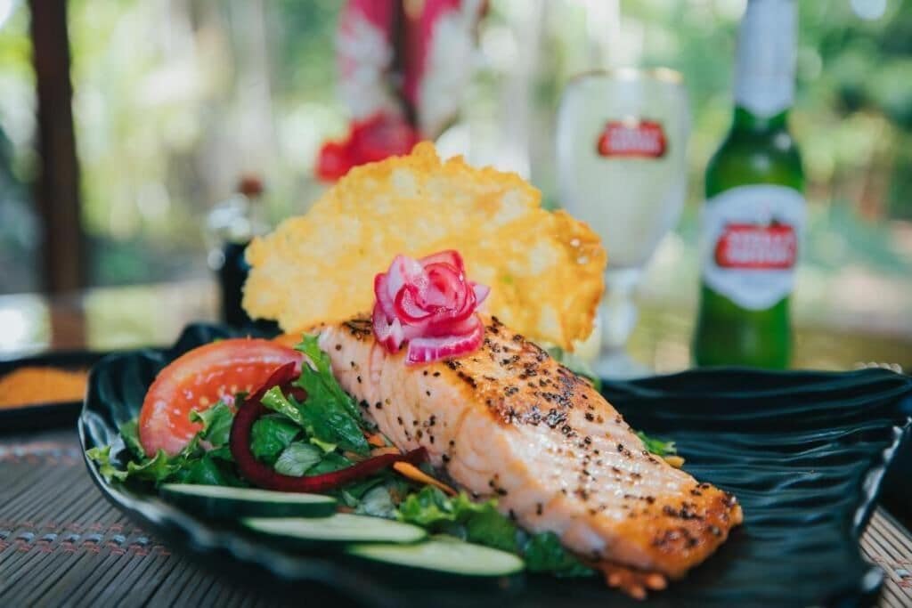 A plate with salmon, salad, and potato chips.