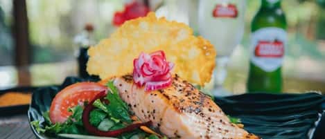 A plate with salmon, salad, and potato chips.