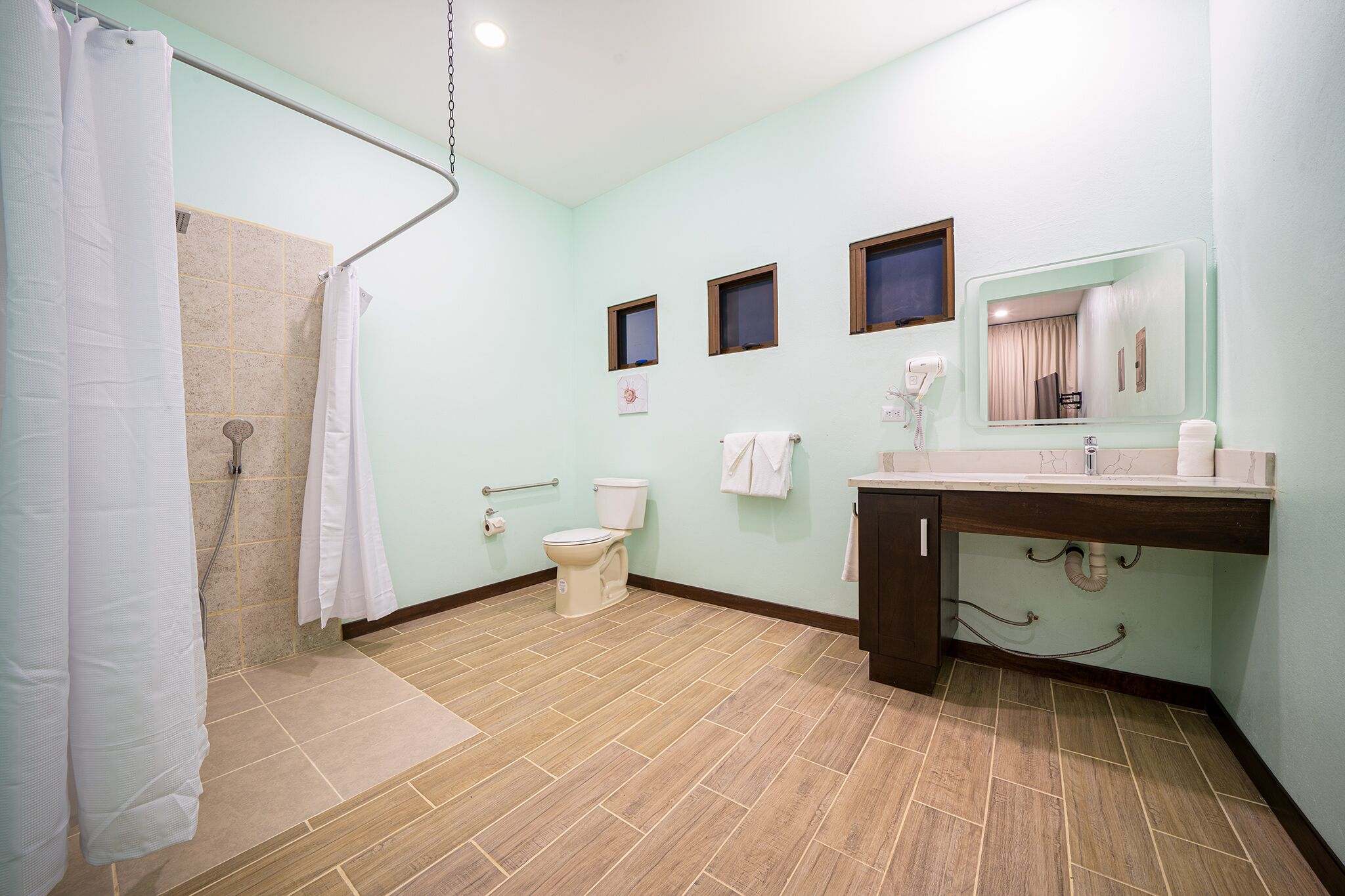 Een badkamer met douche, toilet, wastafel en spiegel.