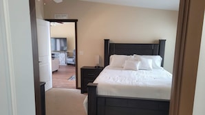 Een slaapkamer met een donker houten bed, witte beddengoed, een nachtkastje en een bureau met een stoel.
