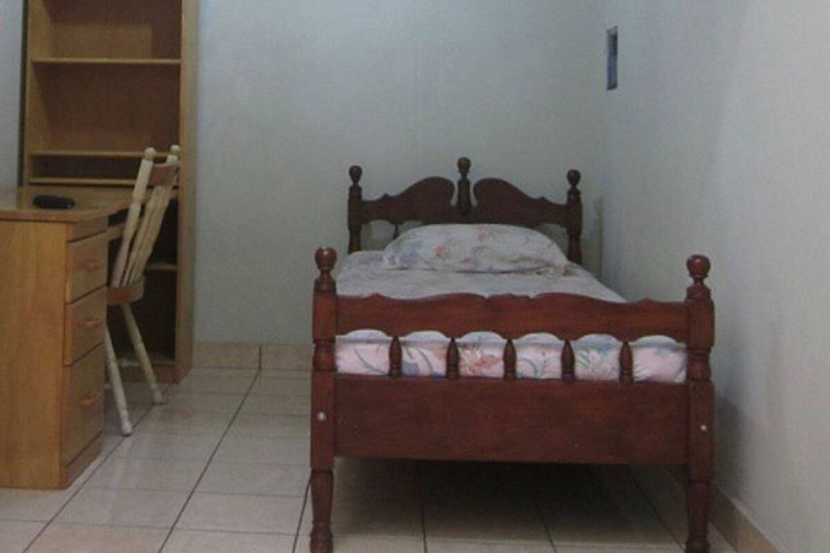 Une chambre à coucher avec un lit en bois, un bureau en bois et une chaise.