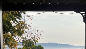 Une terrasse en bois offrant une vue sur une zone verdoyante, des arbres et une chaîne de montagnes lointaine.