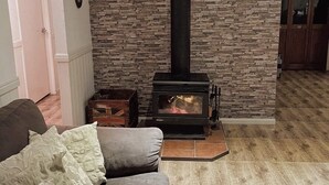 Un salon avec un mur en pierre, une cheminée, un canapé et une table basse en bois.