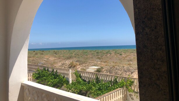 A balcony with a view of a beach and dry vegetation.