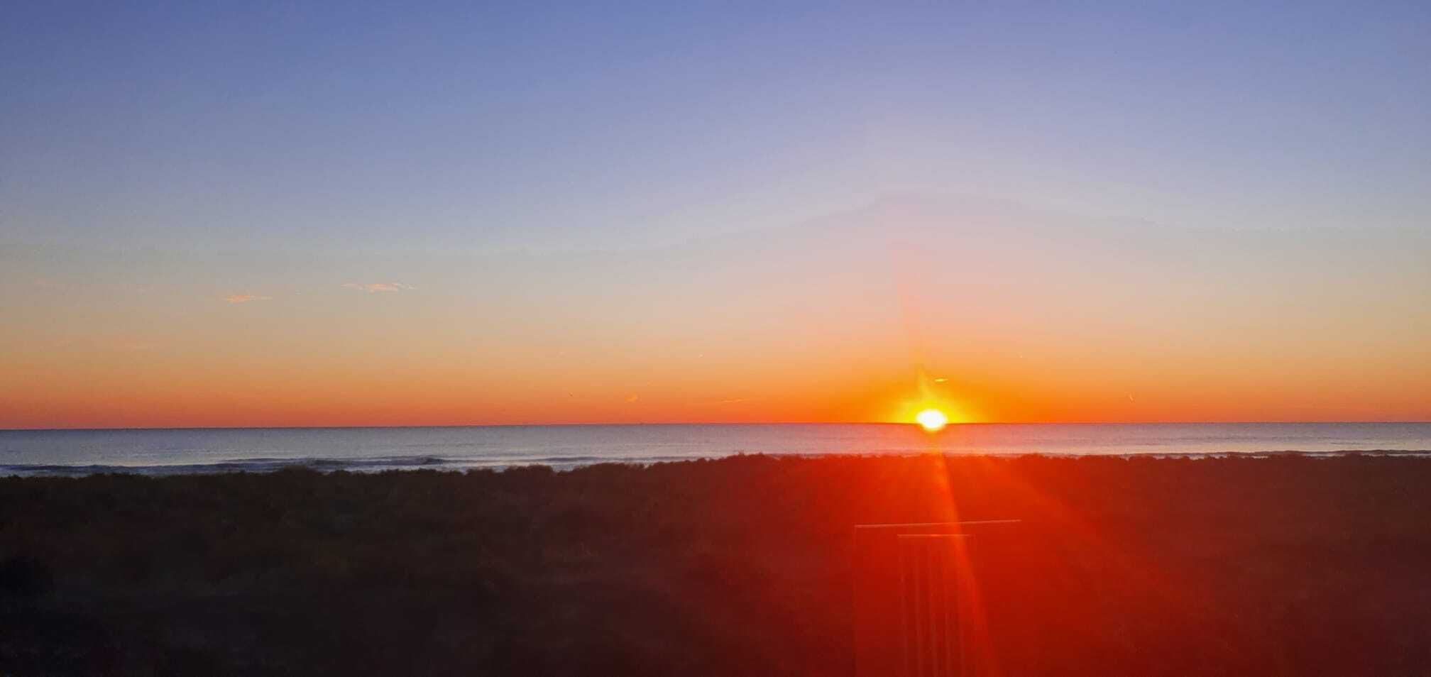 A sunset over a beach with a clear sky.