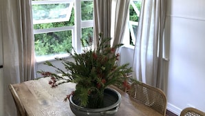 A dining area with a wooden table, a woven pendant light, and a potted plant. - Centrally located "Bargara Beach Cottage" (Bargara)