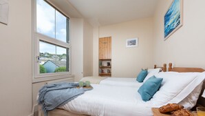 Una camera da letto con un letto, una finestra, uno scaffale in legno e un quadro.